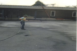 Employee spraying sealer on a parking lot